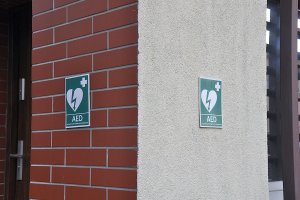 Dwie narożne ściany budynku z tabliczkami zawierającymi logo aede.